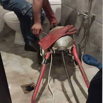 عامل يقوم بتسليك مجاري الحمام بالسوستة الكهربائية
